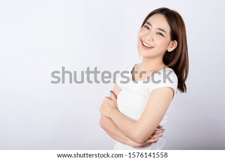 Beautiful young asian stand and pose with big smile happy beaming face in white background. Royalty-Free Stock Photo #1576141558