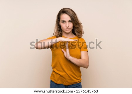Young blonde girl over isolated background making time out gesture
