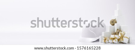 Construction hard hat, white fir tree,  gift boxes and Christmas ornament on a white background with copy space. New Year and Christmas construction background