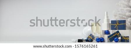 Construction hard hat, white fir tree, two glasses with champagne, gift boxes and Christmas ornaments on a white background with copy space. New Year and Christmas construction background
