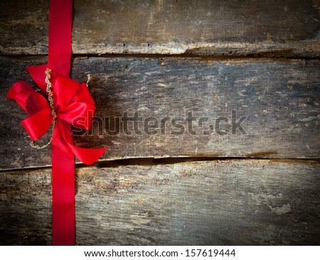 Festive red bow and ribbon forming a border for a Christmas card over rustic wooden planks with copyspace for your greeting or wishes