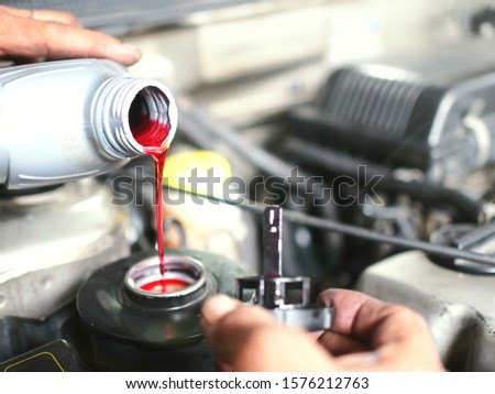 The auto mechanic is refilling additional brake fluid after the inspection and repair of the damaged parts. Royalty-Free Stock Photo #1576212763