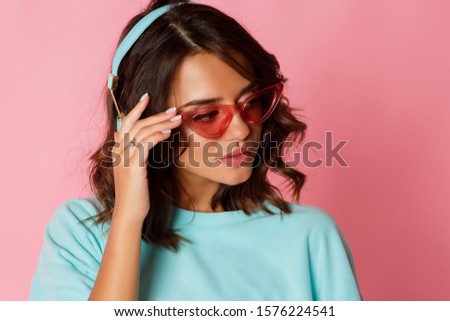 beauty portrait of stylish brunette girl listening music on pink background. 