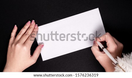 Female hands writing on white paper with feather vitage pen with copy space