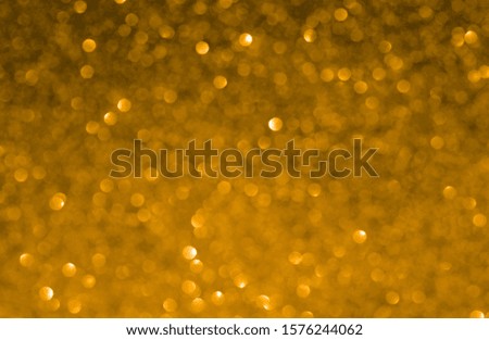 Blurred texture of yellow sparkling glitter paper.
