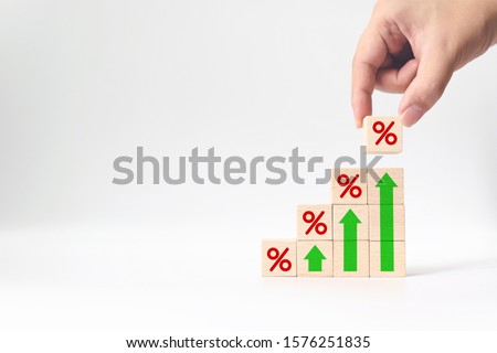 Interest rate financial and mortgage rates concept. Hand putting wood cube block increasing on top with icon percentage symbol and arrow upward direction