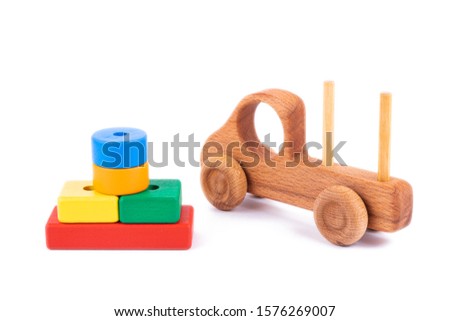 Close-up children's toy made of natural wood in the form of a dump truck  with wooden blocks in the form of multi-colored geometric shapes on a white isolated background. Studio photography. 