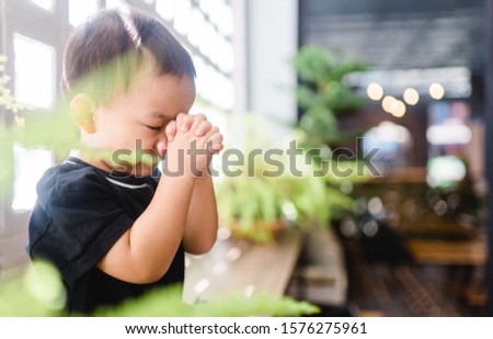 Little asian toddler boy praying and worship to GOD at Church in sunday school.Kid pray to GOD.Hand praying and palm up,Concept Praise and worship with faith, spirituality and Surrender.