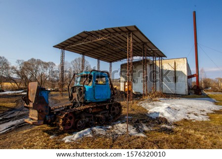 Russian village. An old broken tractor stands against a brick boiler room in a Russian village.