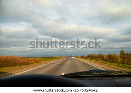 Track from the car window and white clouds on blue sky. Driver seeing beautiful autumn landscape during travel in auto