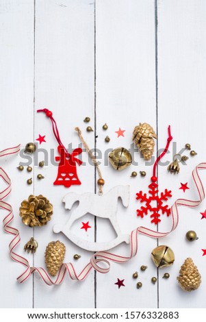 rocking horse, golden cones and red felt Christmas decorations on white wooden table background