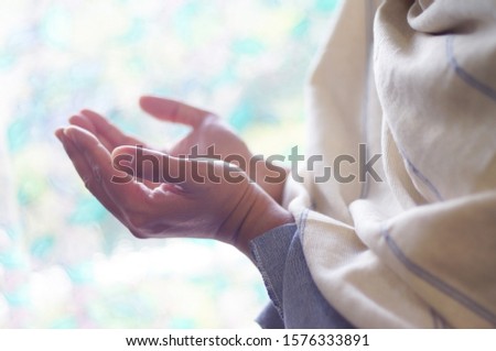 Hands of men is praying at windows, Focus at white silk at right side of picture.