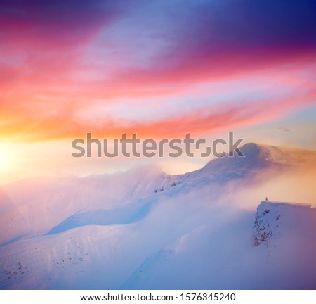 Hiker on the edge of a cliff on snowy hills. Location place ski resort Dragobrat, Carpathian, Ukraine, Europe. Epic picture of winter journey. Great nature wallpapers. Discover the beauty of earth.