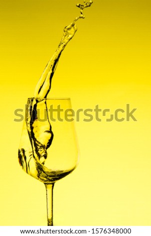 beautiful splashes of water in a wine glass, with yellow filter, close up with copy space.