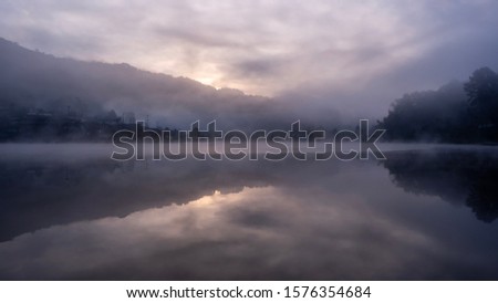 Lake view misty morning of reservoir around with soft mist with yellow sun light in the sky background, sunrise at Ban Rak Thai, Mae Hong Son, northern of Thailand. ,bluerred image