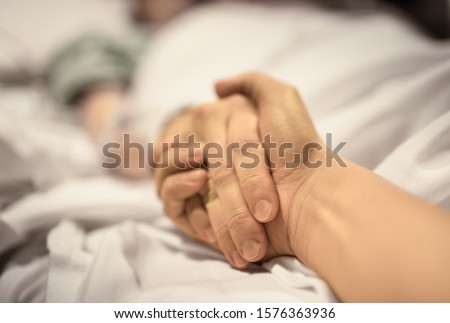 Man holding hand, giving support and comfort to woman, loved one sick in hospital bed. 