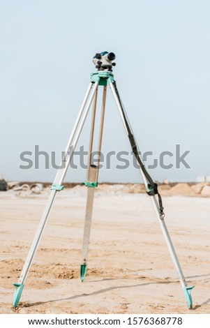 Digital level for geodesic measuring on dirt road with blue sky at background