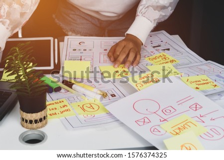 Web designer planning mobile application content of prototype on document design software ux architect on table office. Developer creative display production on user interface project in technology