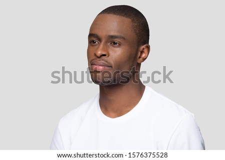 Three quarter portrait of attractive confident millennial African American man, handsome young male wearing white t-shirt, serious guy, student posing close up isolated on studio background