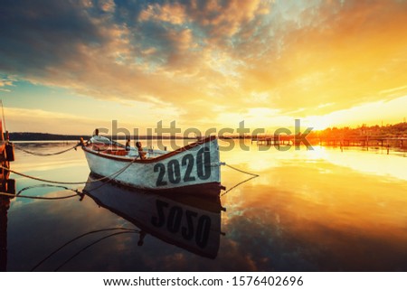 2020 concept Fishing Boat on Varna lake with a reflection in the water at sunset.