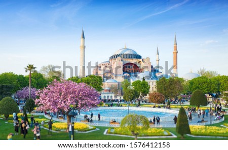 Low aerial view of Sultanahmet district in Istanbul, Turkey. Walking people, green grass fields and fountain near famous Hagia Sophia. Bottom of photo is blurred so that people are unrecognizable. Royalty-Free Stock Photo #1576412158
