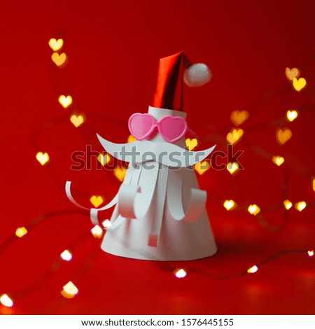 Craft paper figure of Santa Claus on red with love sun glasses, heart lights on background. Christmas holiday celebrate. Cartoon modern bauble.