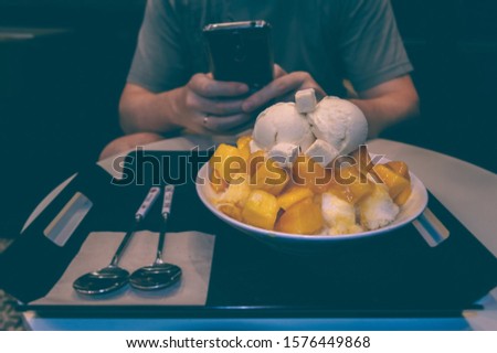 man is taking photo of mango bingsoo - korean shaved ice dessert with sweet toppings