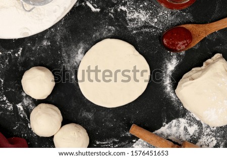 prepare dough, pizza with rolling pin and flour, sauce tomato on black background top view