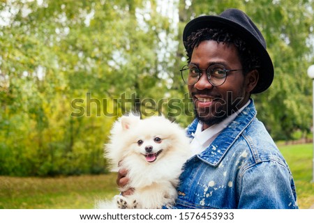 afro man hugging his fluffy spitz in park