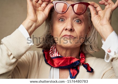 surprised woman with glasses and light clothes a scarf around her neck                               