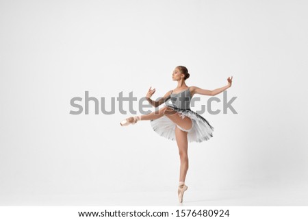 Ballerina in pointe and tutu on an isolated background with a leg raised up