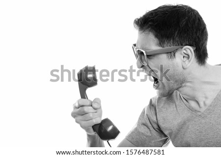 Close up of angry young man shouting at old telephone