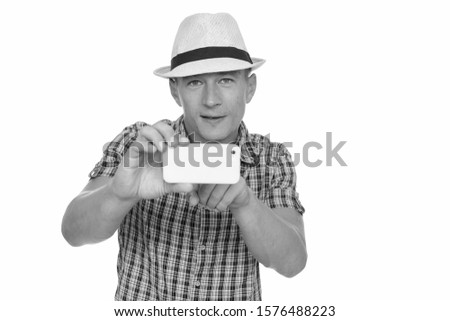 Studio shot of young handsome Caucasian man taking picture with mobile phone isolated against white background