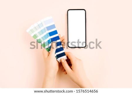 Female hand holding color swatches and  smartphone mockup. Color trend palette. 