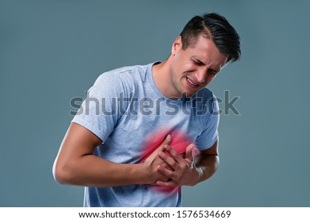 People, healthcare and health problem concept - unhappy young man having heart attack or heartache over gray  background. Royalty-Free Stock Photo #1576534669