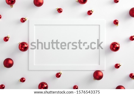 Christmas minimal mockup - red xmas ball on white background. Horizontal composition with white paper frame. Flat lay, top view. Copy space