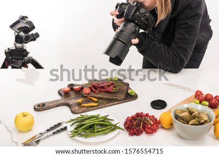 female photographer making food composition for commercial photography and taking photo on digital camera 