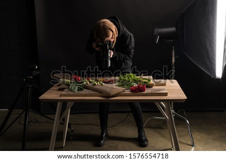 female photographer making food composition for commercial photography and taking photo on digital camera 