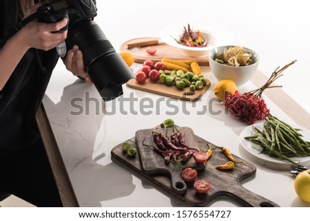 cropped view of female photographer making food composition for commercial photography and taking photo on digital camera 