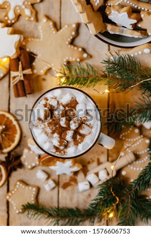 Winter hot drink: white mug with hot chocolate with marshmallow and cinnamon. Cozy home atmosphere, festive holiday mood. Rustic style, wooden background. Homemade gingerbread cookies. Flat lay