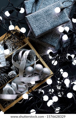 Christmas decoration of gifts, garland, boxes in packing paper, black background, ribbons