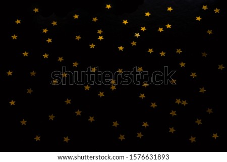 Gold stars on a black background. Christmas and New Year background of gold confetti stars.
