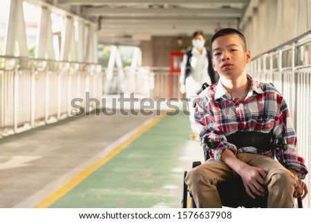 Portrait of Disabled child on wheelchair, Public bridge background with blurry, Special children’s enjoying outdoor activity at a normal life,Life in the education age ,Happy disability kid concept.