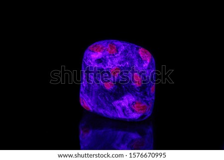 macro mineral stone ruby under ultraviolet light on a black background close-up