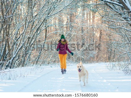 Portrait Young woman in winter park walking with her dog golden retriever. Friendship, pet and human.
