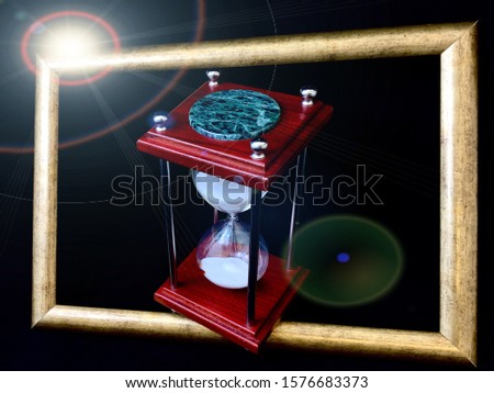 Hourglass in a wooden frame, on a black background. Glass hourglass in a frame for a picture. Glass time meter. Concept: time is running out, time is valued, time management