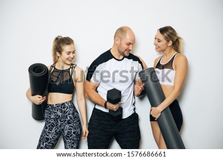 Young sports girls and boy are engaged in fitness, lifestyle, sports and healthy eating, in the gym girls do exercises,On a white background posing in a sports hall