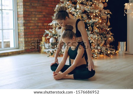 Woman and girl doing yoga in Christmas. 