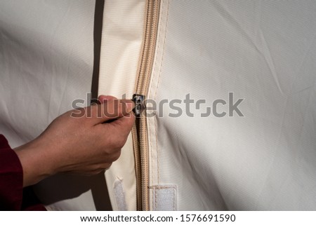 People hand is sliding zip part of camping tent to close/open the door. Camping activity close-up action photo.
