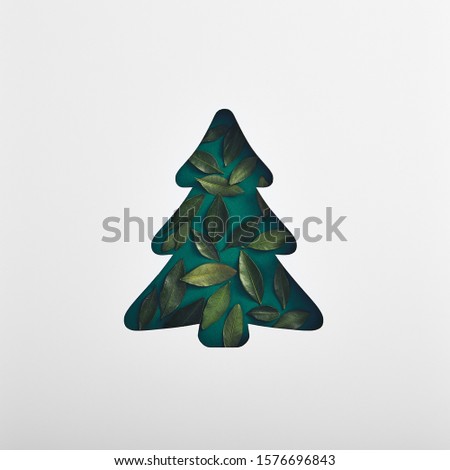 Christmas minimal concept - xmas tree silhouette made with green leaf. Square composition, flat lay, view from above. Luxury festive background. Xmas celebration.